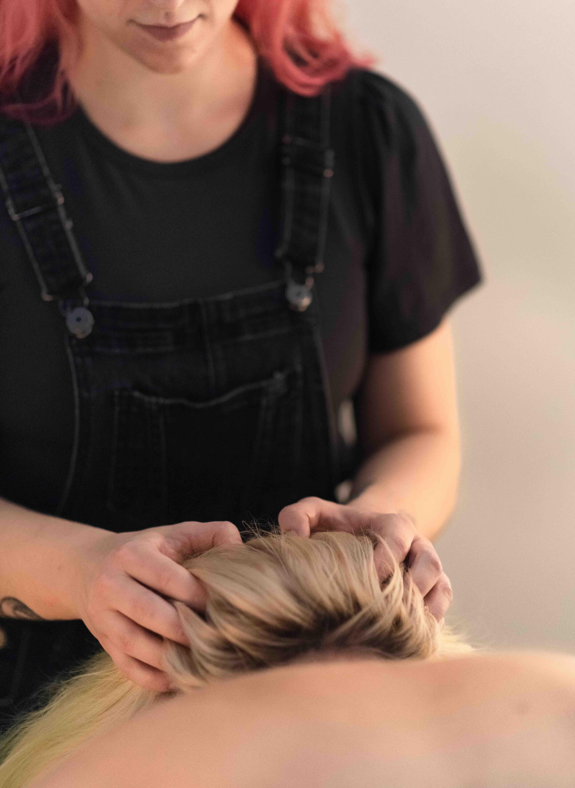 a massage therapist's hands are shown providing a scalp massage to a patient with blonde hair